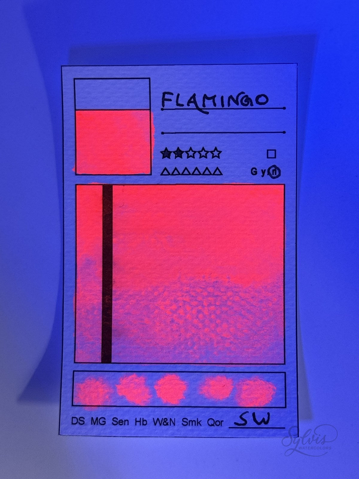 kleine Farbkarte Flamingo – handgemachte Aquarellfarbe auf Aquarellpapier, beleuchtet mit UV Licht, zeigt den UV Leuchteffekt