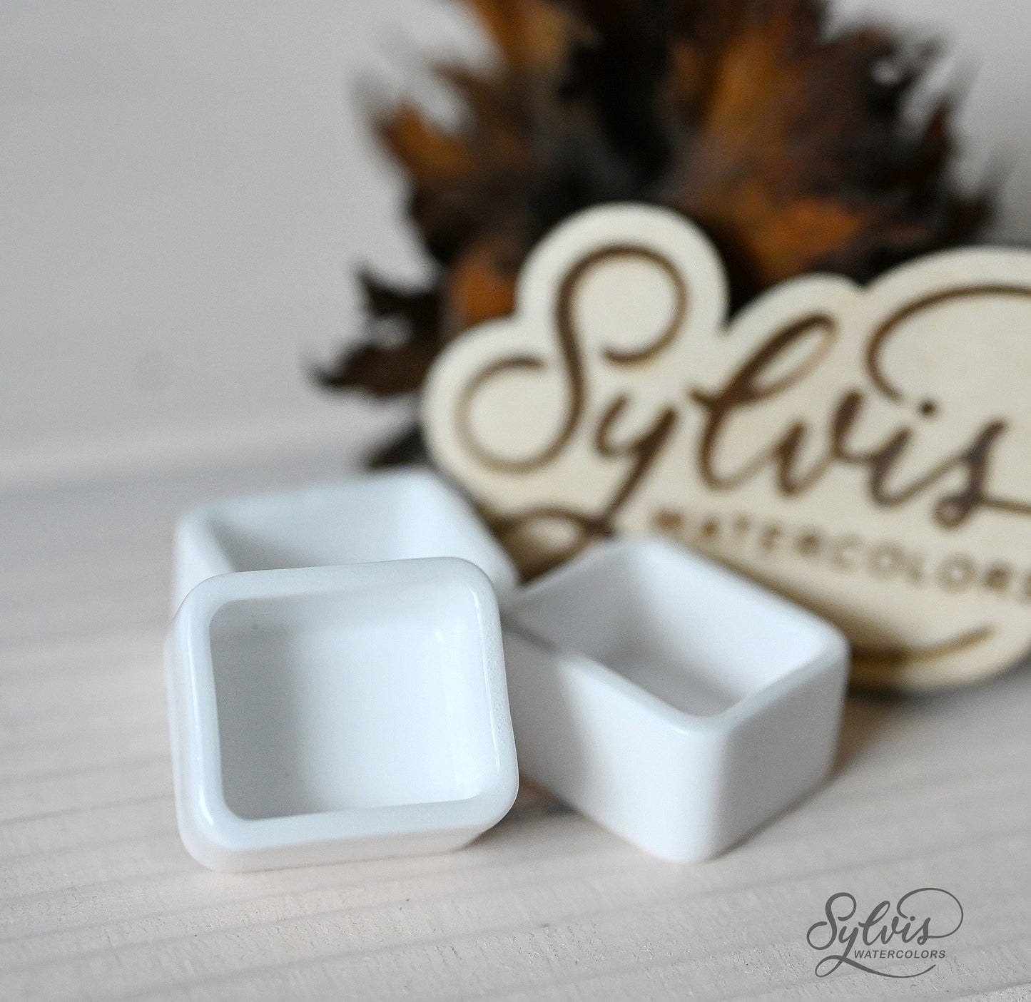 Nahaufnahme halbe Näpfchen aus glasierter Keramik im Hintergrund Holzlogo und Deko