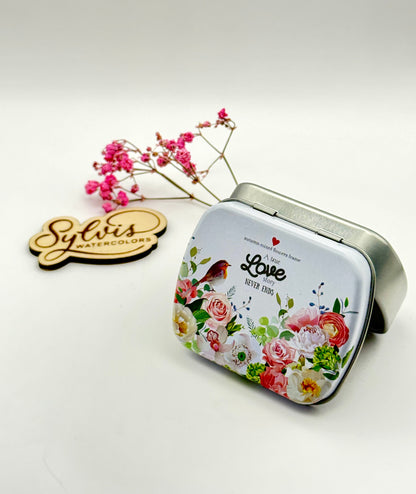 kleine Weißblechdose mit silbernem Unterteil und weißlackiertem Deckel mit buntem Blumenmuster und Rotkehlchen