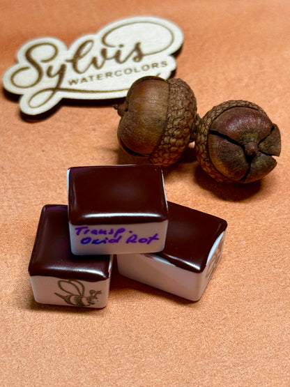 drei halbe Näpfchen Transparent Oxid Rot auf Farbswatch liegend, Eichel als Deko und Holzlogo im Hintergrund