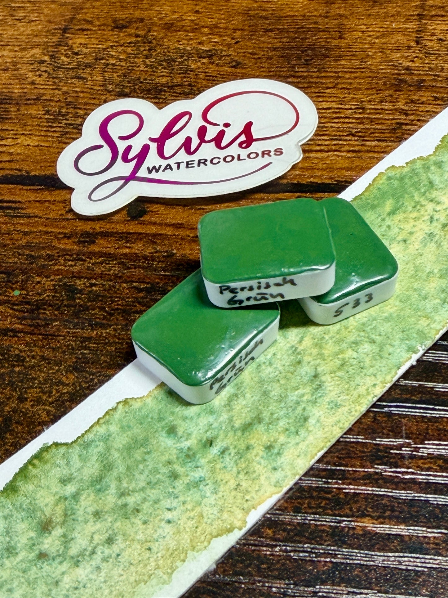 Viertel Näpfchen Aquarellfarbe Persich Grün im Vordergrund Farbswatch, im Hintergrund Sylvis Watercolors Logo