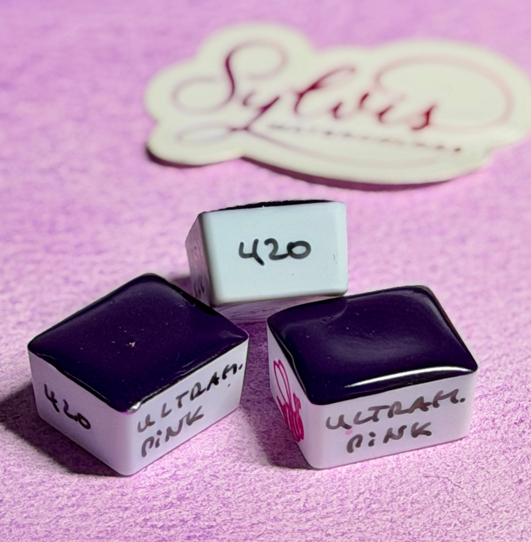 Halbe Näpfchen mit Ultramarine Pink im Hintergrund Sylvia Watercolors Logo