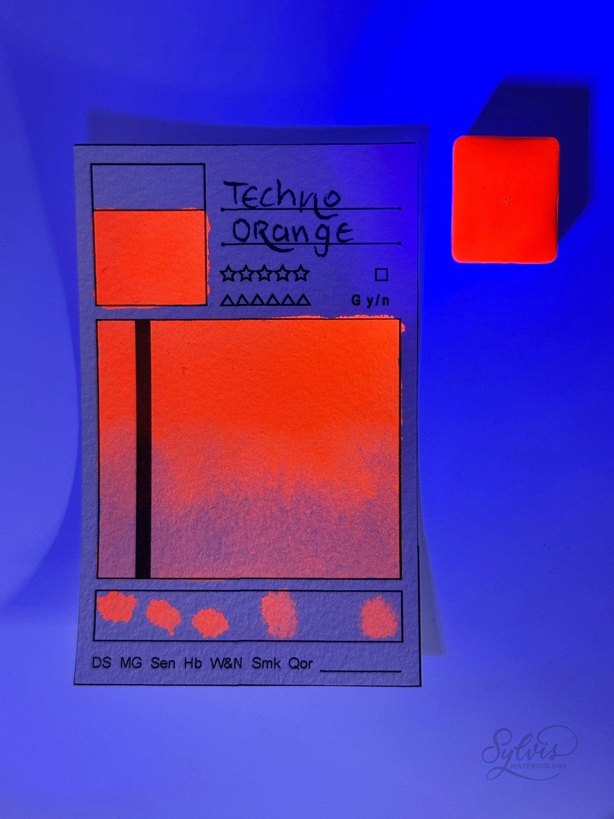 kleine Farbkarte Techno Orange – handgemachte Aquarellfarbe auf Aquarellpapier, Neon, UV-aktiv - mit UV Licht angestrahlt um den Leuchteffekt zu zeigen.