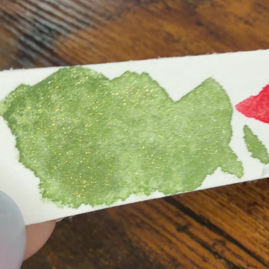Farbswatch von Temple Green und Temple Ember auf Aquarellpapierstreifen, als Video, um in Bewegung den Glitzereffekt zu zeigen
