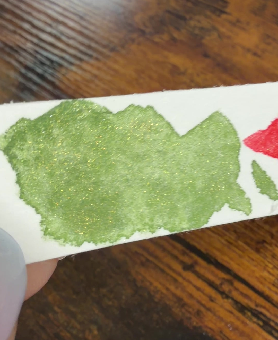 Farbswatch von Temple Green und Temple Ember auf Aquarellpapierstreifen, als Video, um in Bewegung den Glitzereffekt zu zeigen